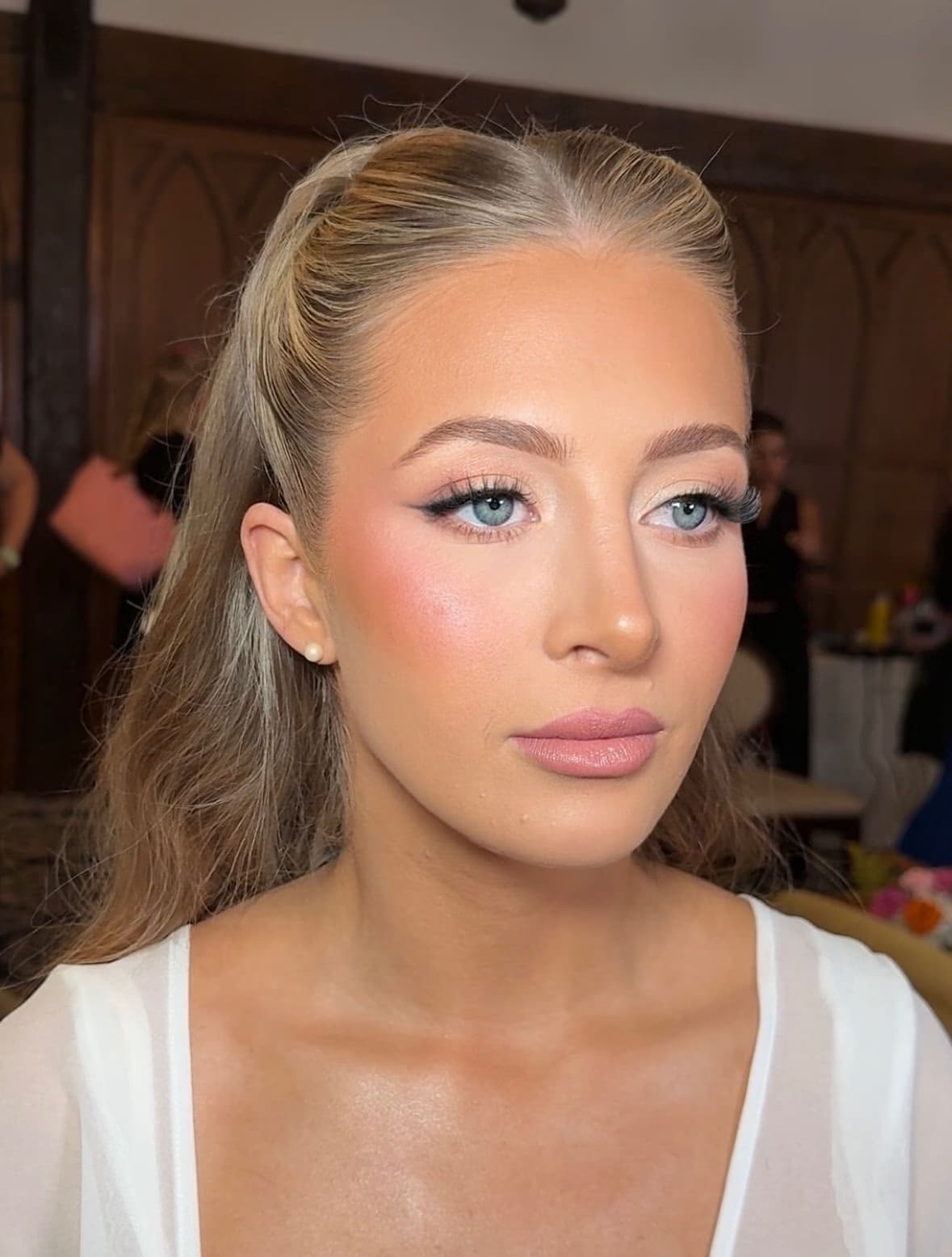 British bride in Abu Dhabi with blue eyes, sleek half-up blonde hair, winged liner and luminous natural bridal makeup by Elani Artistry