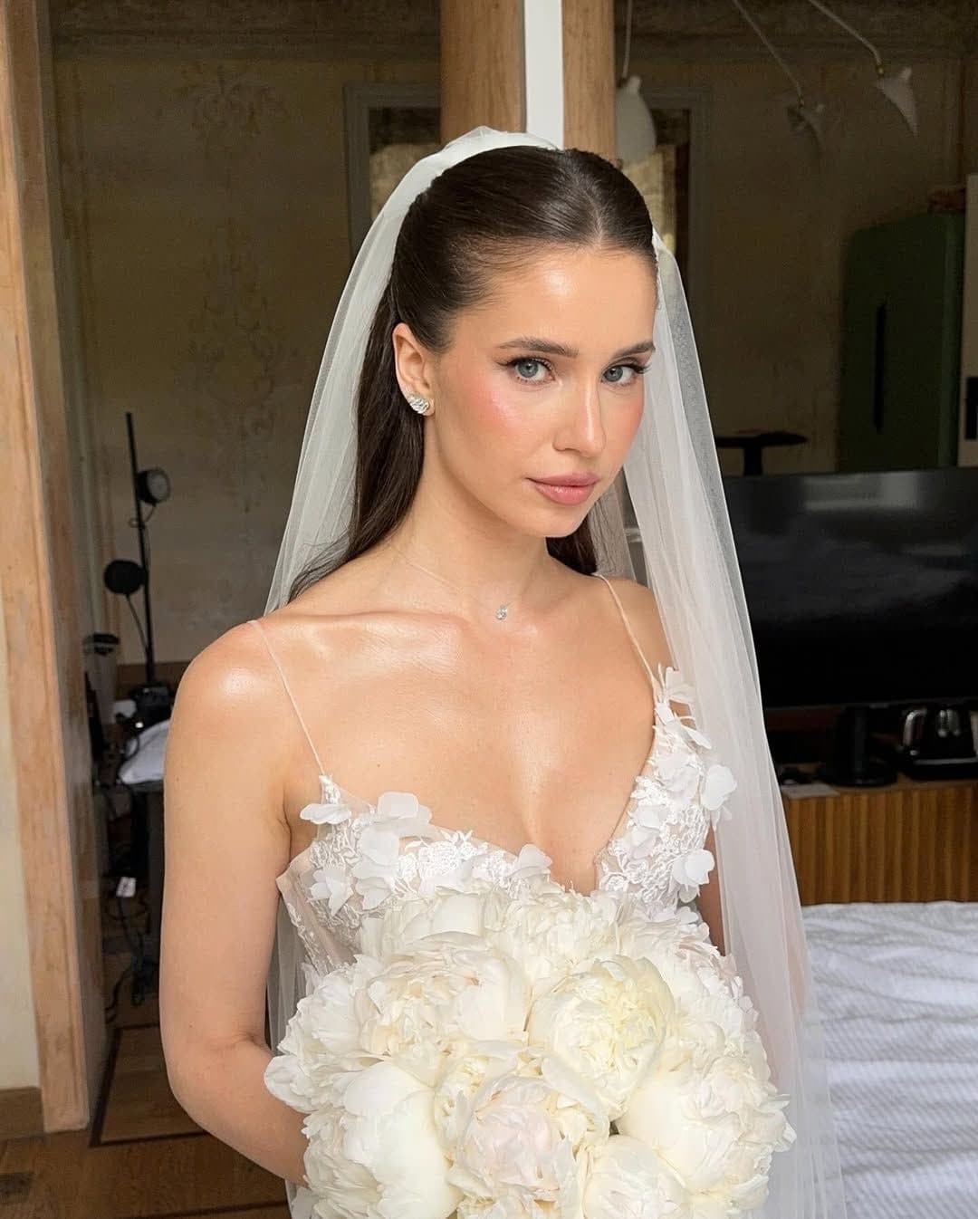 Minimalist bride in Abu Dhabi with flawless glowing skin, sleek ponytail veil and white peony bouquet, clean bridal makeup by Elani Artistry