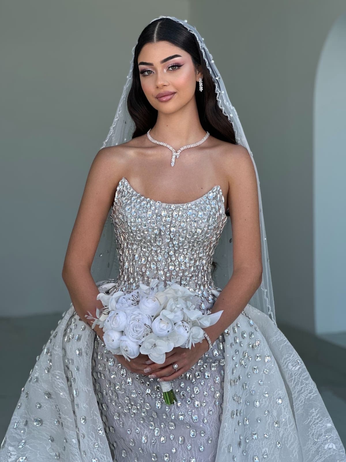 Western-cultural fusion bride in Abu Dhabi in crystal-embellished white gown with veil and diamond necklace, polished bridal makeup by Elani Artistry