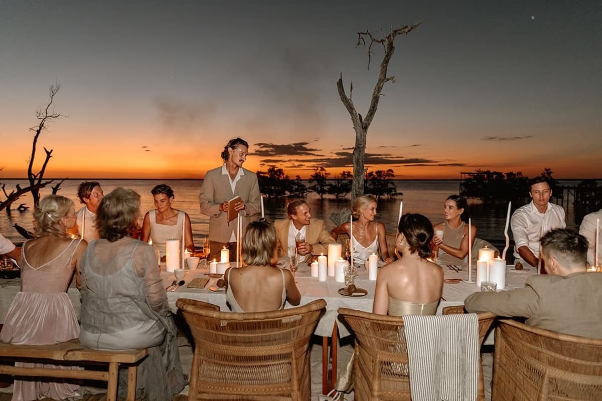 Wedding dinner party at sunset on an African beach with candles and driftwood, destination wedding makeup by Elani Artistry