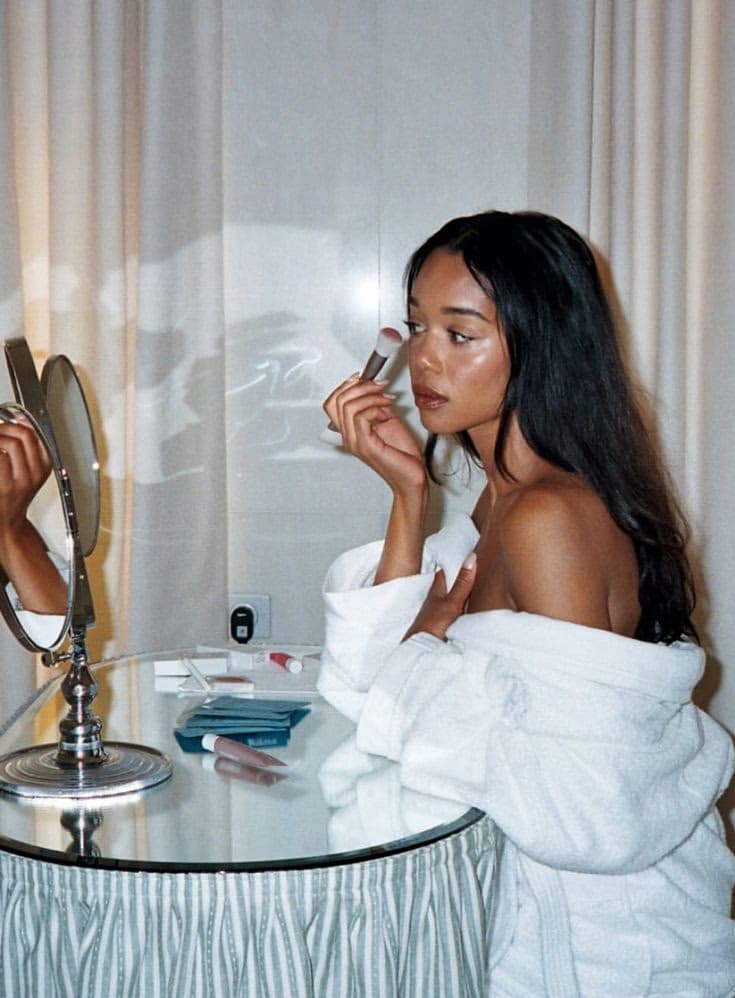 Woman applying blush with a brush in front of a bathroom mirror, one-to-one self makeup lesson with Elani Artistry Dubai