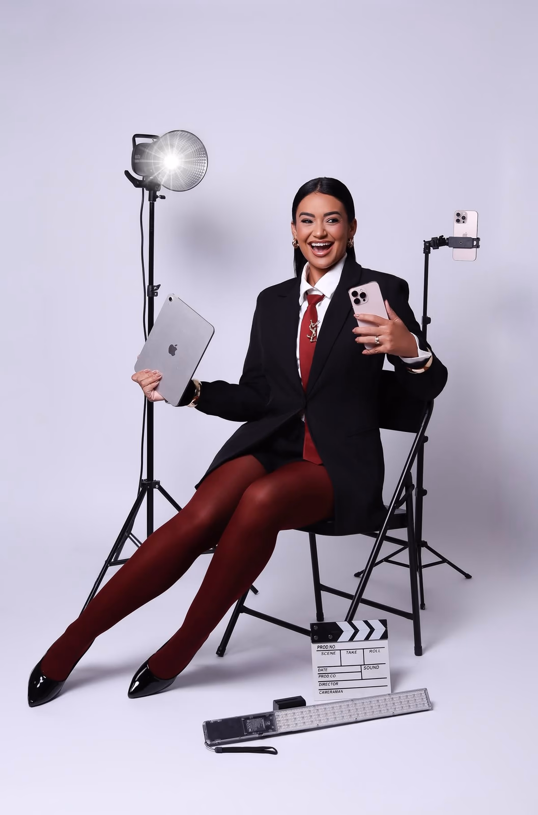 Content creator holding phone and tablet with studio lights and clapperboard, build a presence that gets bookings Elani Artistry Dubai